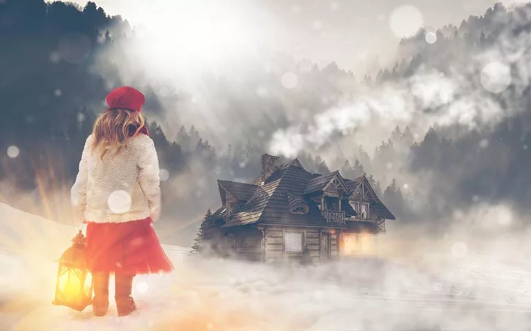 little girl looking at a cottage in the snow