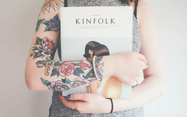 woman with tatoos holding a book