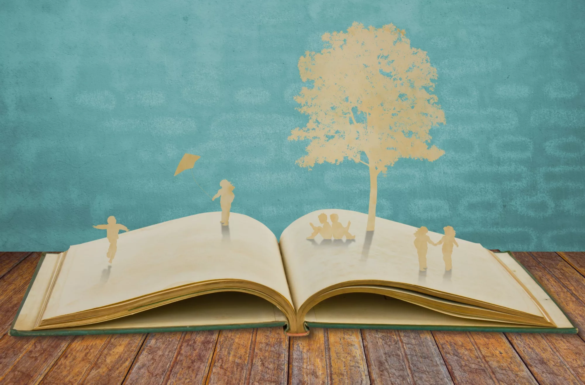 paper cutouts of people and a tree on top of an open book